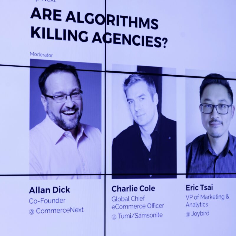 A display showing a panel discussion titled "Are Algorithms Killing Agencies?" featuring Allan Dick, Charlie Cole, and Eric Tsai.