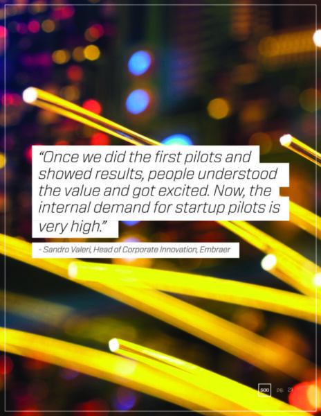A quote from Sandro Valeri, Head of Corporate Innovation at Embraer, against a colorful, abstract background. The quote emphasizes the success and high demand for startup pilot programs at Embraer.